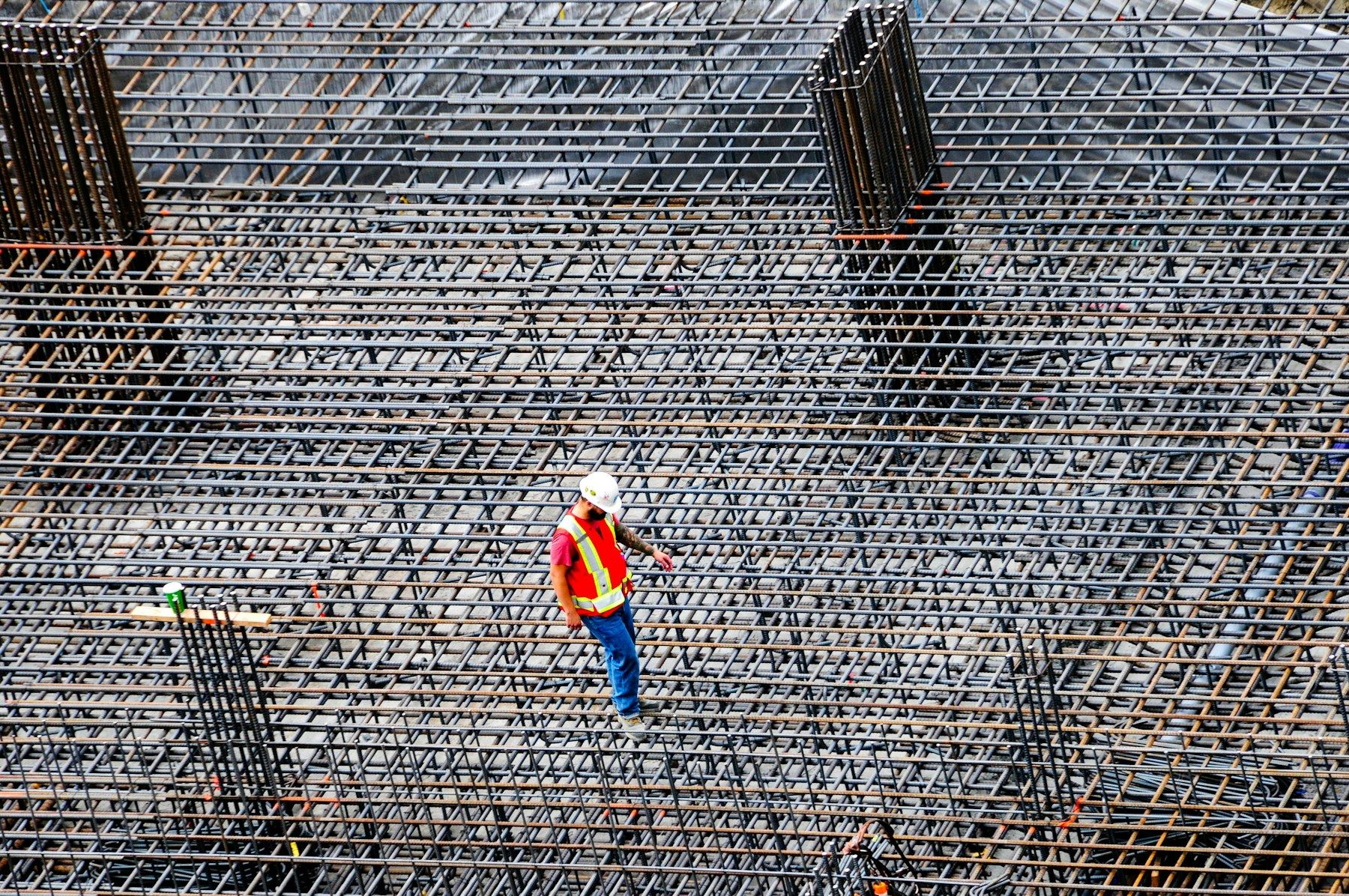 Construction worker inspecting a reinforced steel mesh on site